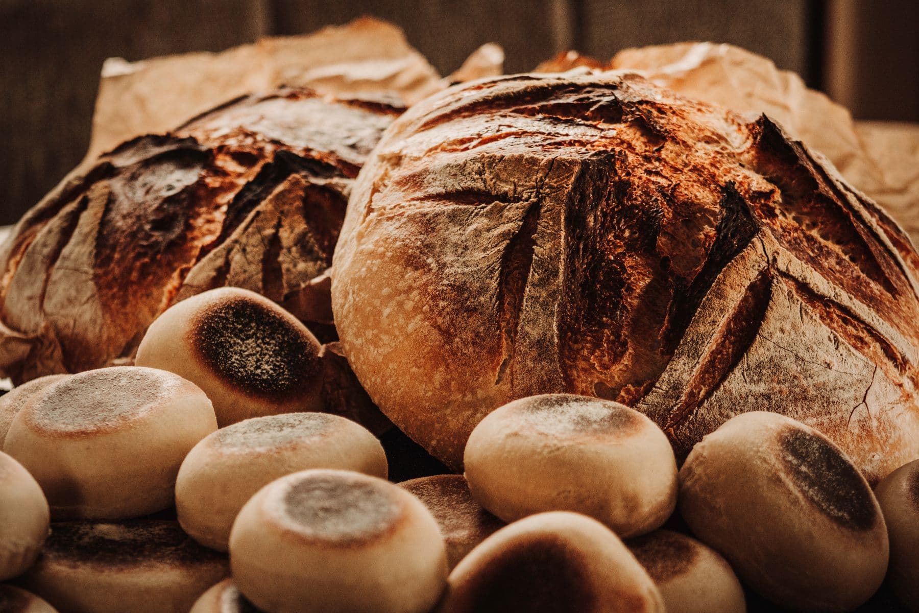 Rustic scored sourdough loaves and soft rolls cooling together
