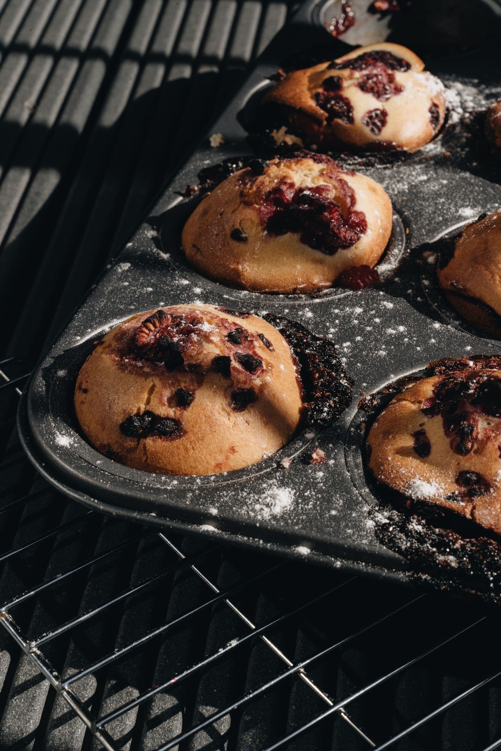 Muffins fresh from the oven, berries breaking through the tops
